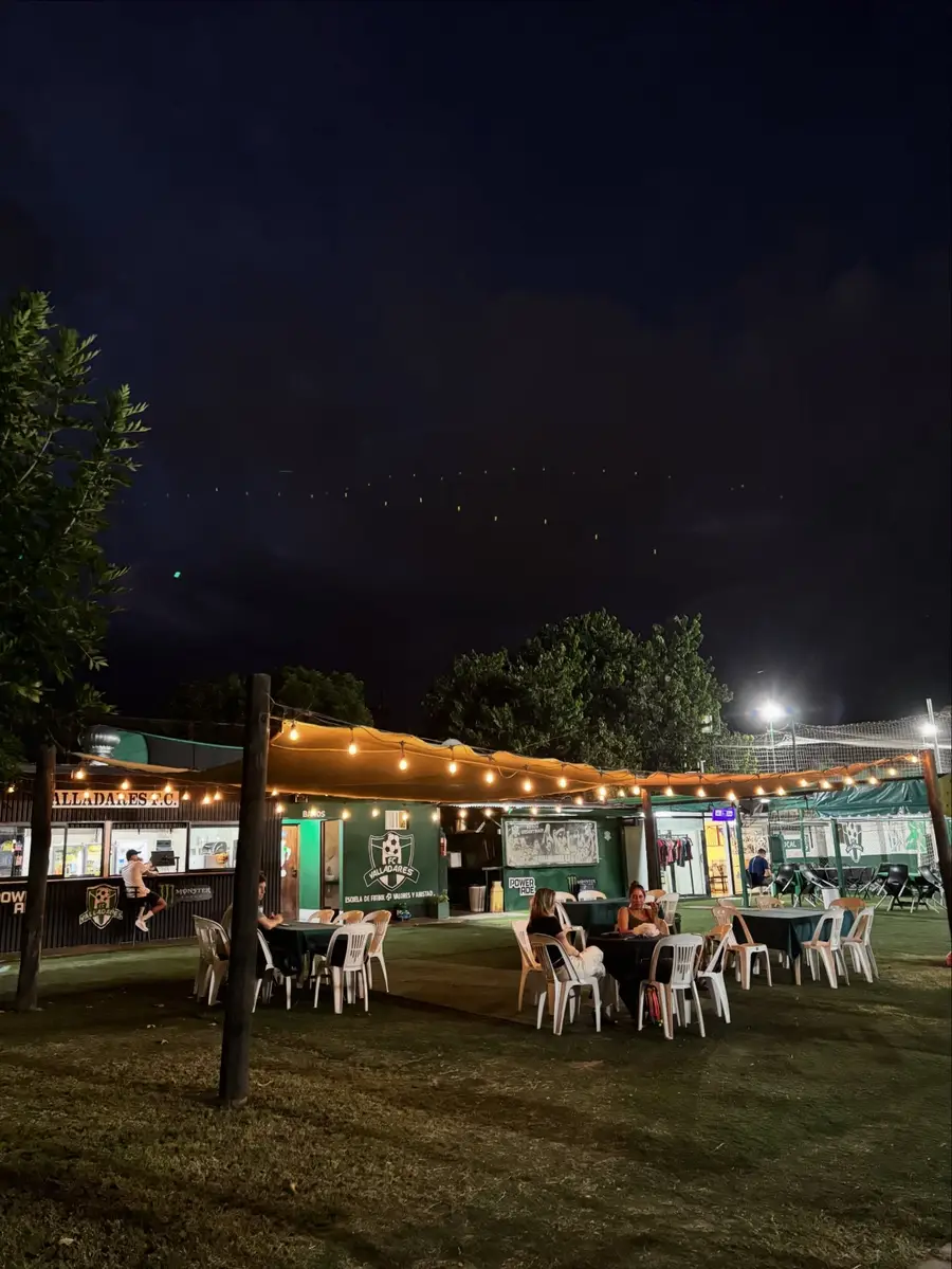Quincho del predio con guirnaldas de luces y canchas al fondo